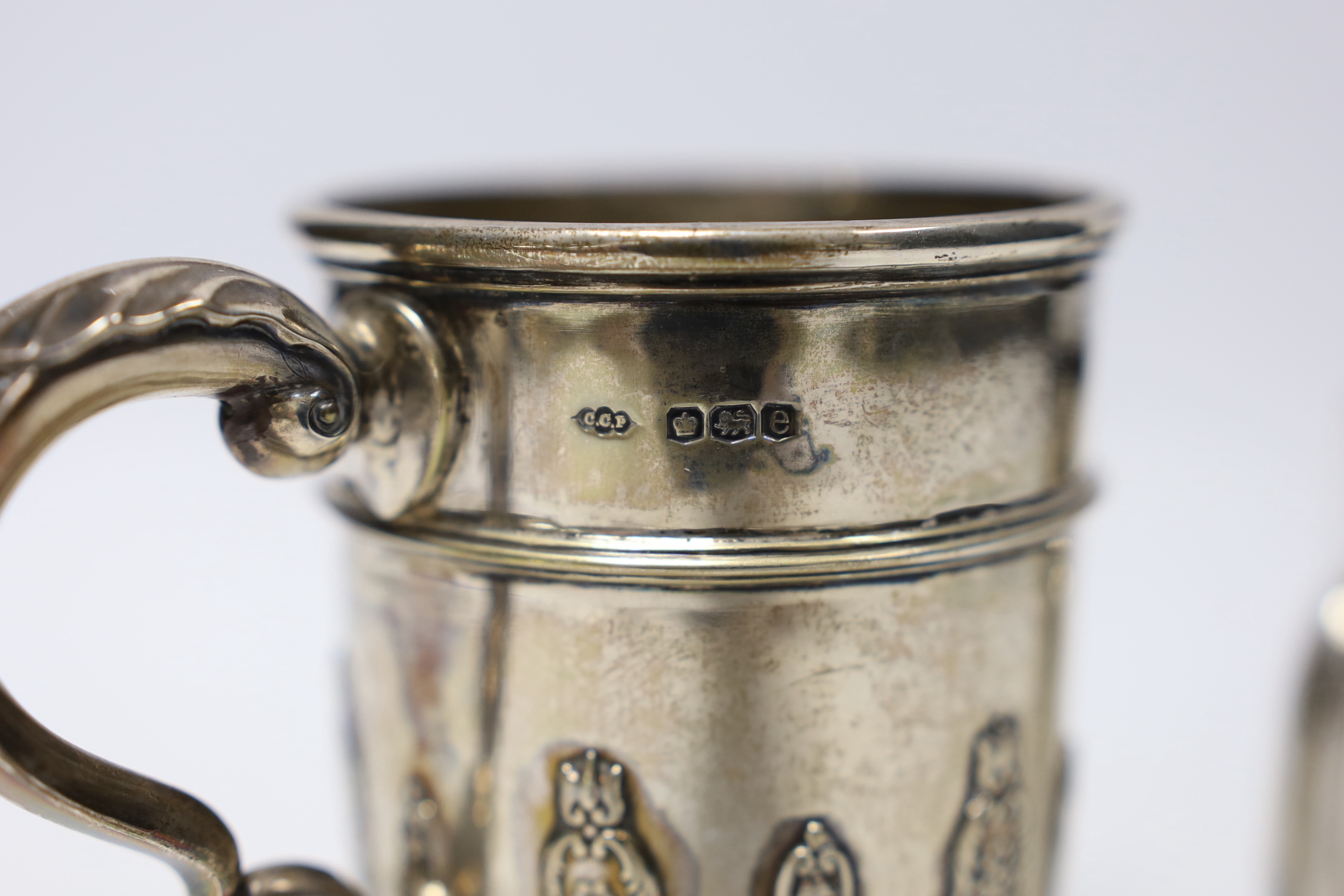 A George V silver christening mug, with card cut decoration, Sibray, Hall & Co, Sheffield, 1922, height 10.1cm and one other smaller George V silver christening mug, 8.7oz.
